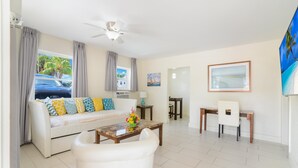 A living room with a sofa, coffee table, and a dining area with a table and chairs. - Soleado Hotel (Fort Lauderdale)