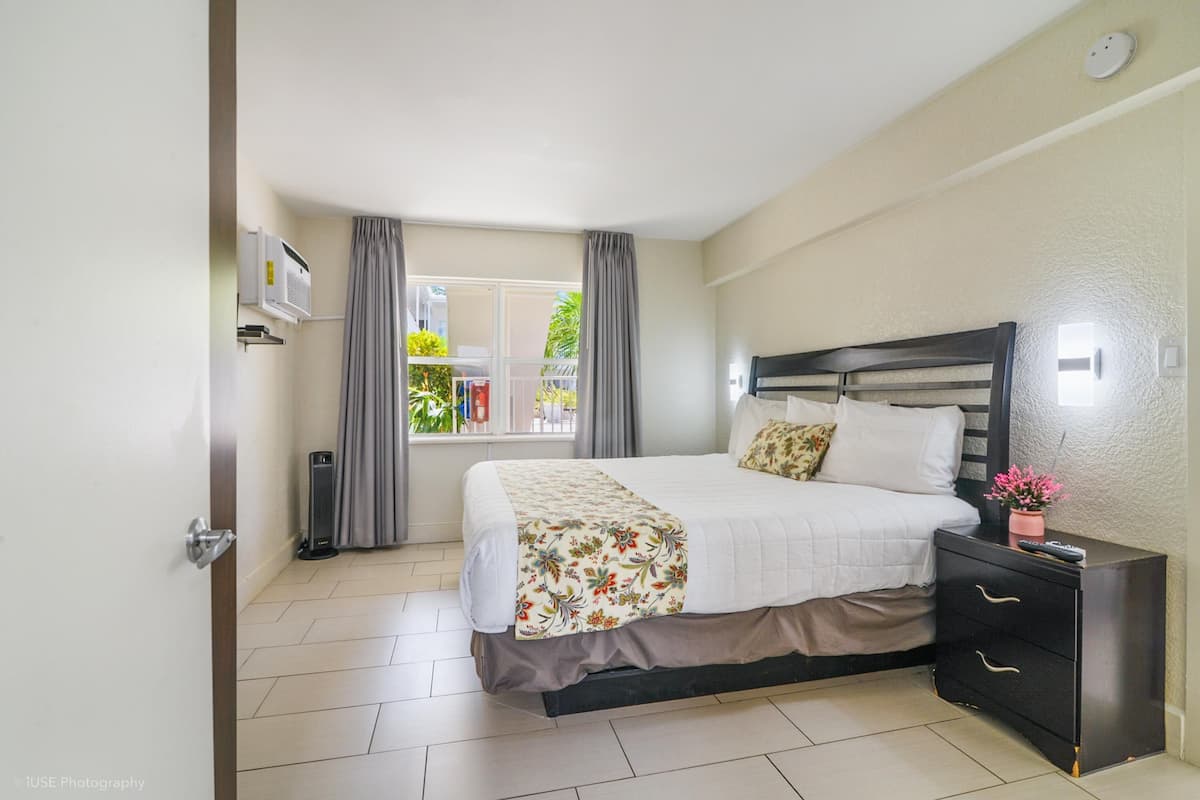 A bedroom with a bed, bedside table, and a window with curtains.
