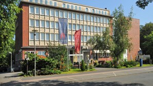 Un hôtel à plusieurs étages, doté d’une façade en briques, de grandes fenêtres et d’un drapeau devant l’entrée.