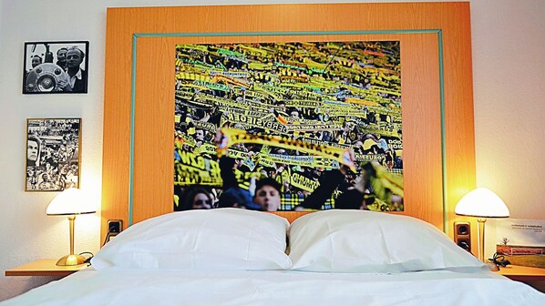 Habitación de hotel con una cama grande, dos lámparas de noche y una pared decorada con cuadros.