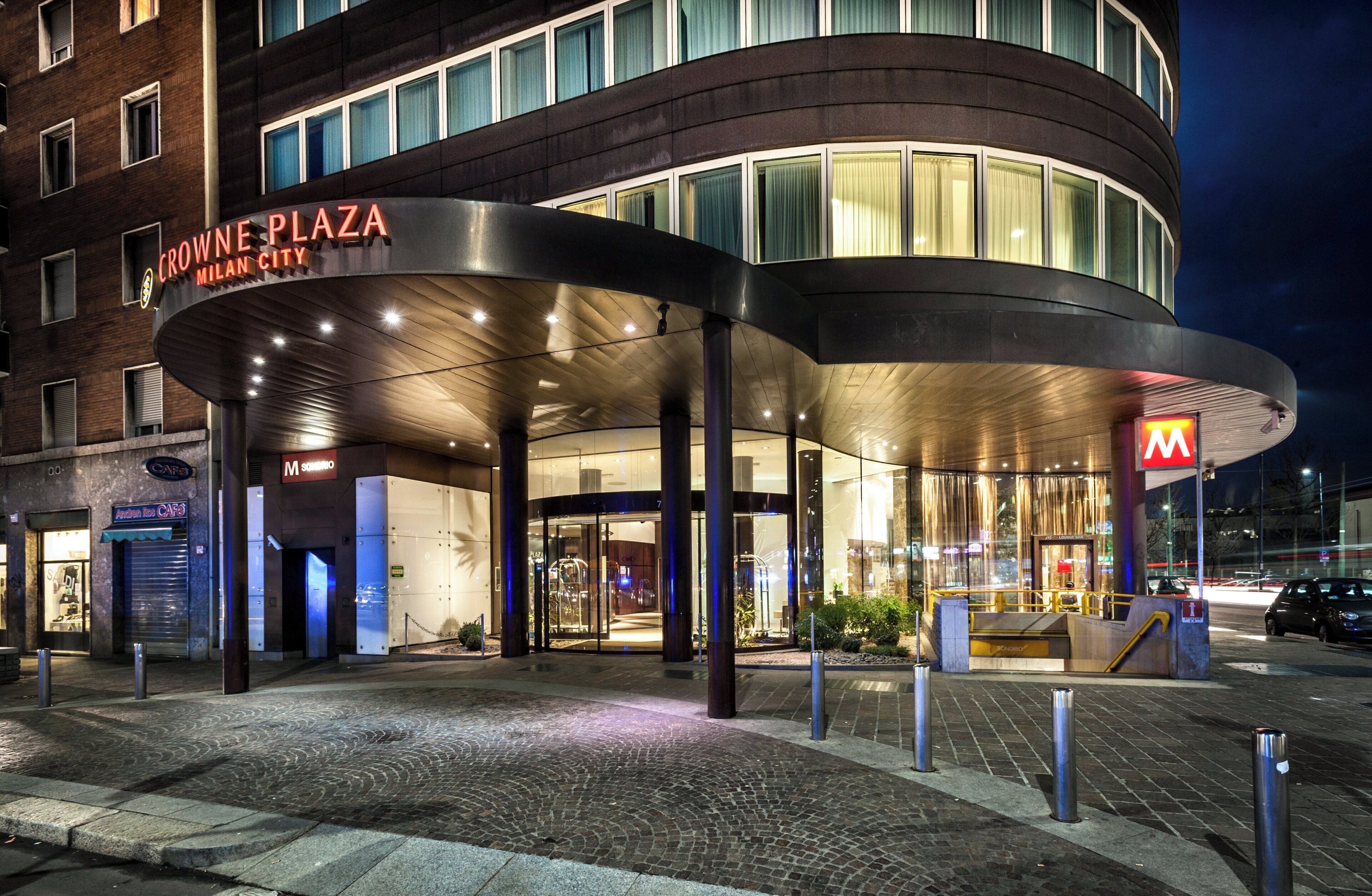 Ingresso di un hotel con facciata curva e ingresso ben visibile, con insegna 'Crown Plaza'.