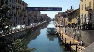 A canal flanked by buildings, a boat docked on the right, and a bridge overhead.