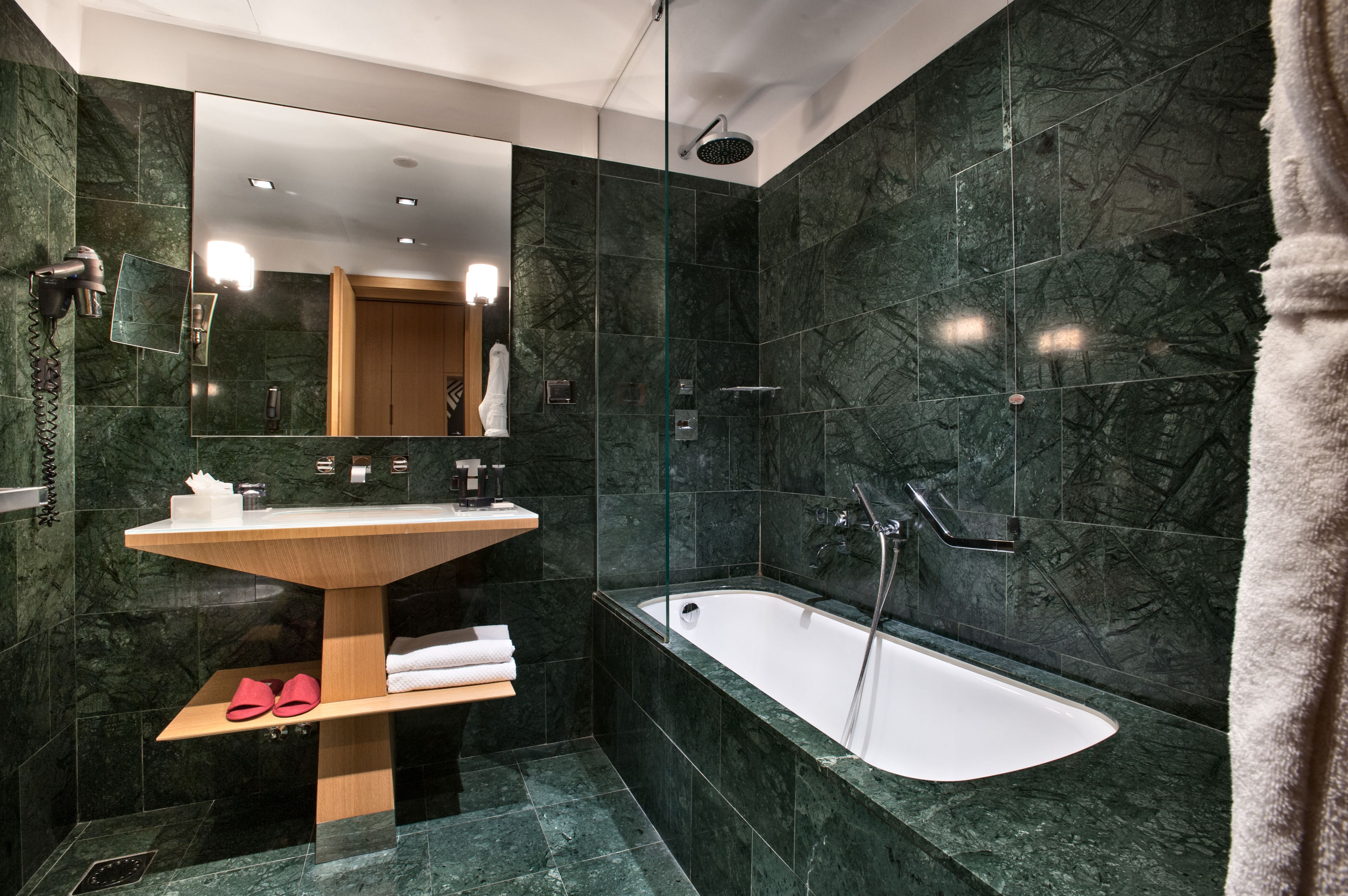 Un bagno moderno con un lavandino a colonna libera, una vasca da bagno e uno specchio grande.