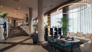 A modern lobby with a staircase, seating area, and a reception desk.
