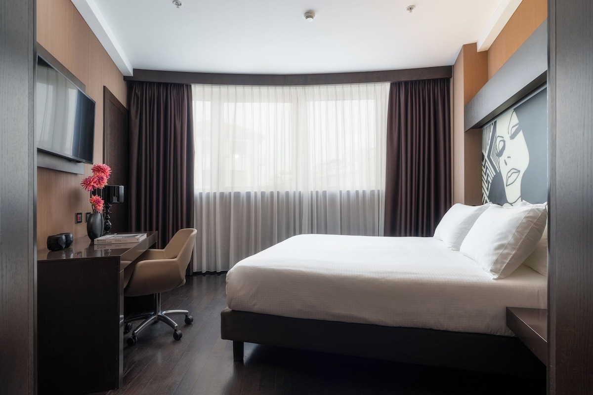 Une chambre d’hôtel moderne avec un grand lit, un bureau et une télévision.