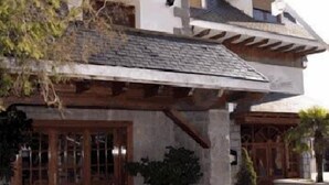 A traditional stone building with a wooden porch and a stone entrance. - Rural Hotel Las Gacelas (Becerril de la Sierra)