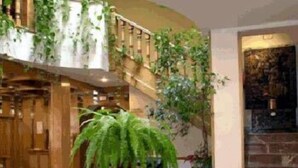 A lobby with a staircase, a large potted plant, and a stone wall. - Rural Hotel Las Gacelas (Becerril de la Sierra)