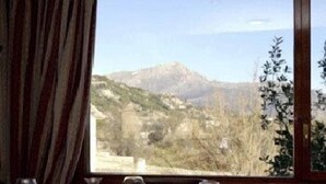 A dining table with plates of food and wine glasses, set against a window with a mountainous view. - Rural Hotel Las Gacelas (Becerril de la Sierra)