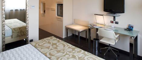 A hotel room with a bed, a desk, a chair, a television, and a small table.