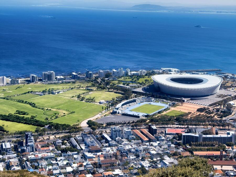 A stadium with a circular design surrounded by residential buildings and a golf course.