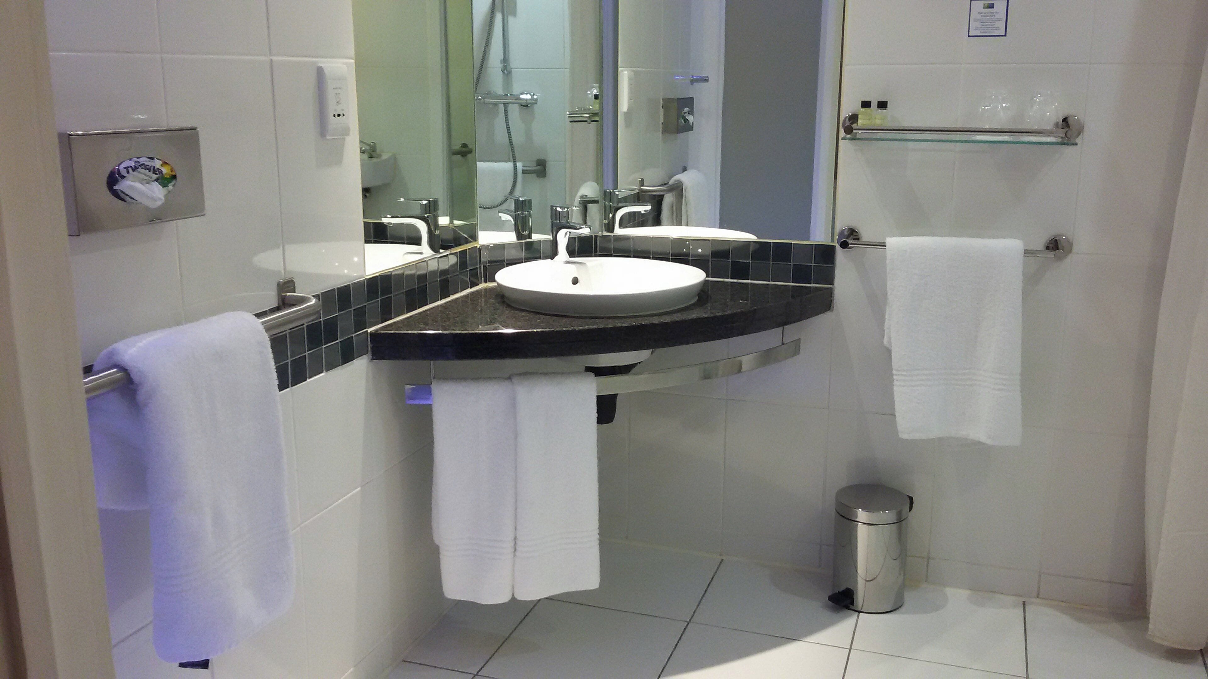 A modern bathroom with a white sink, black countertop, and a glass shower enclosure.