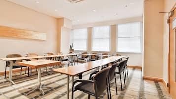 Un salón de conferencias con una mesa larga, sillas y una alfombra estampada.