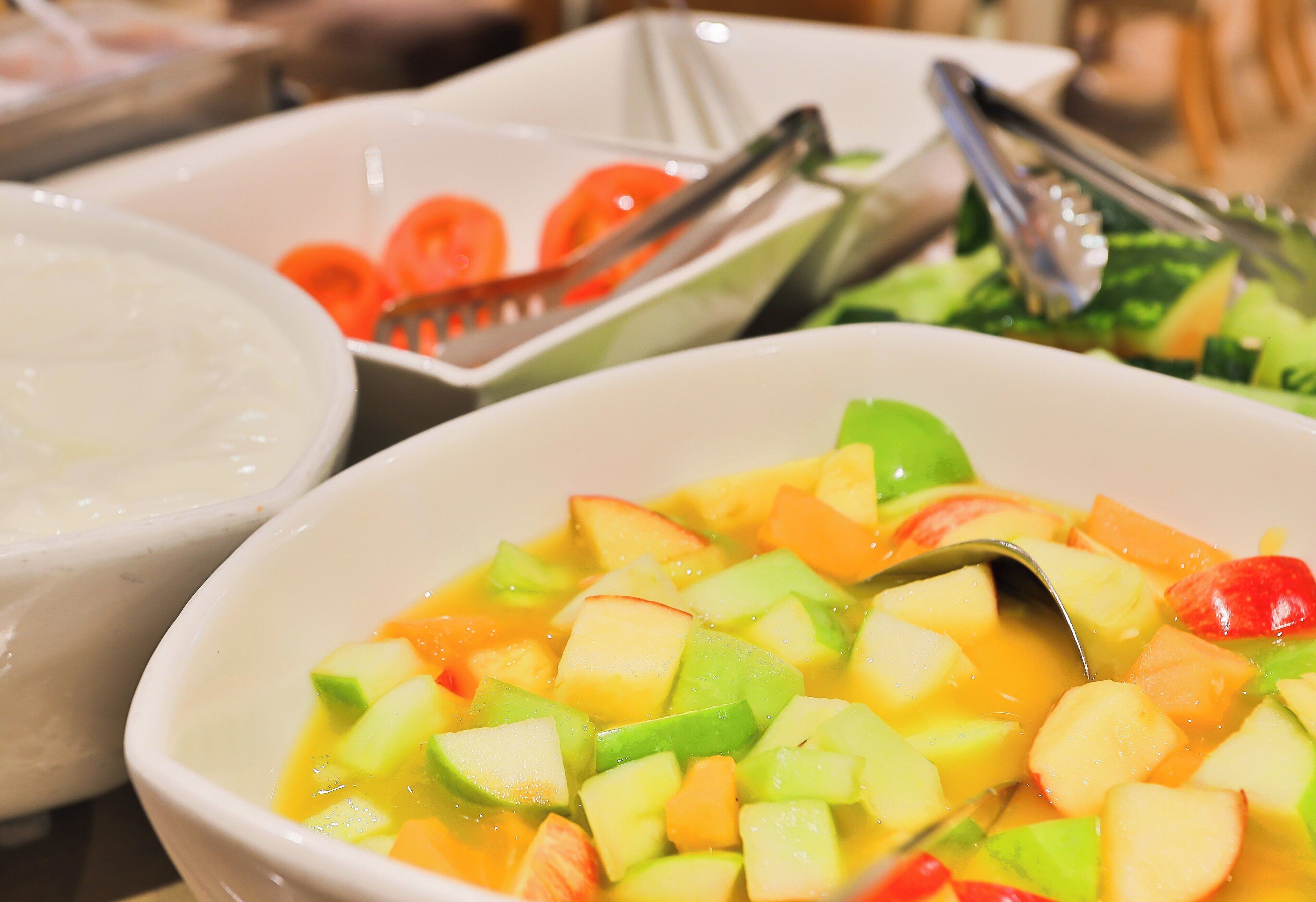 Un saladier rempli d’une salade de fruits variés, avec une cuillère à côté.