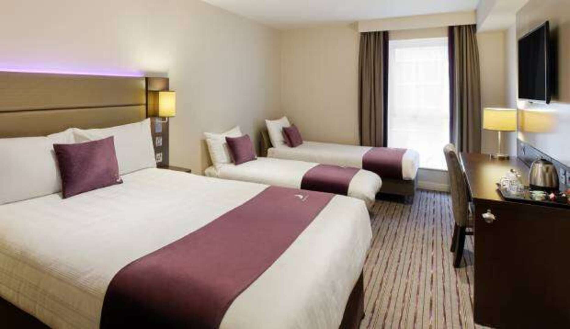Une chambre d’hôtel avec deux lits, un bureau et une télévision.