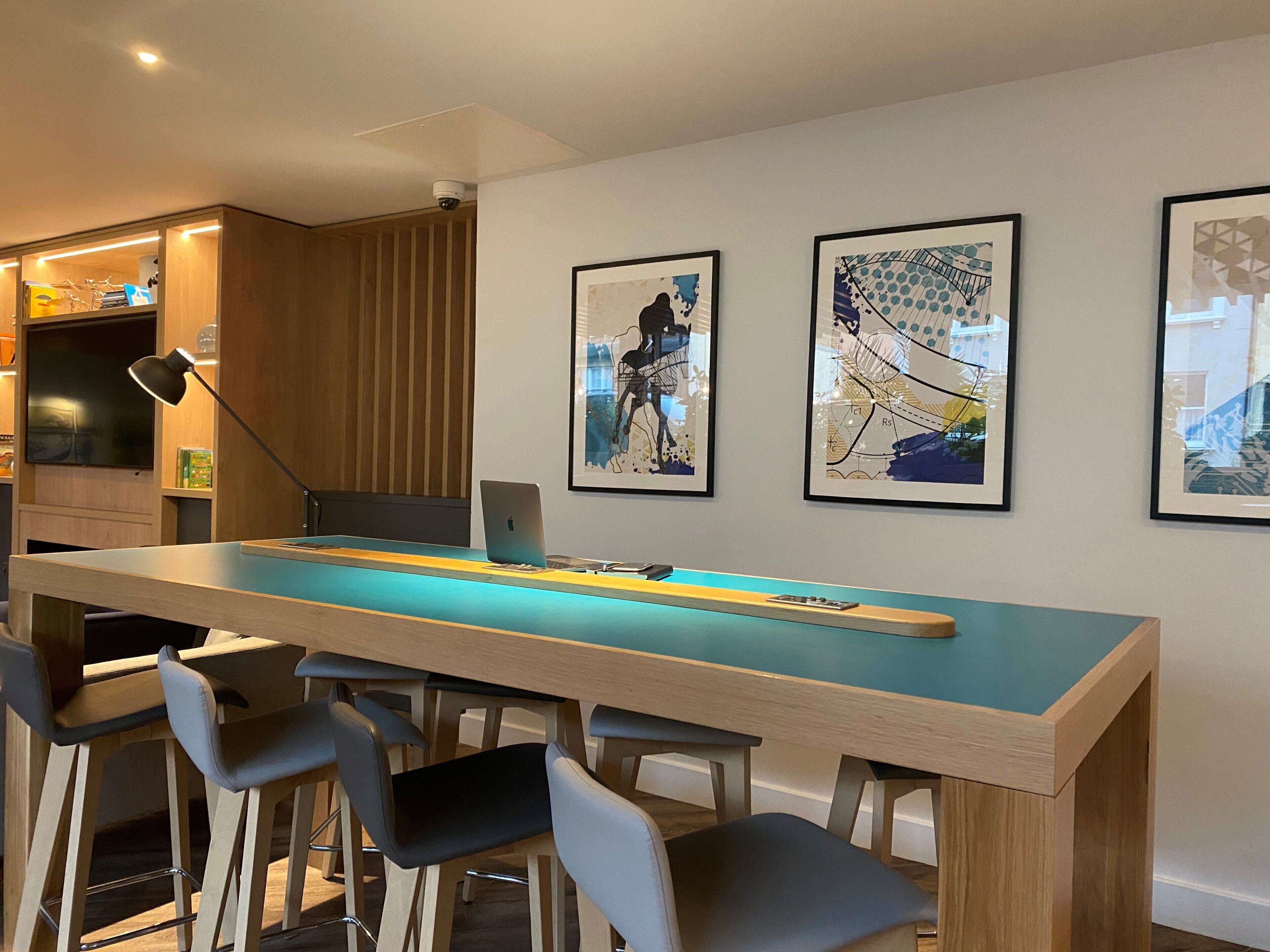 Una cocina moderna con una isla central grande, taburetes de bar y cuadros en la pared.