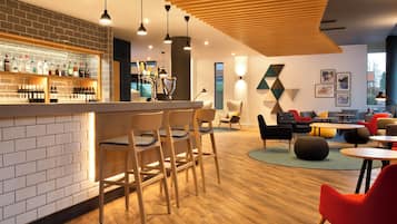 A modern bar area with a brick wall, wooden chairs, and a variety of bottles.