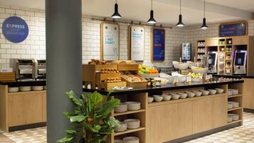 A breakfast buffet area with a variety of food items, including pastries and fruits, and a sign indicating breakfast is included.