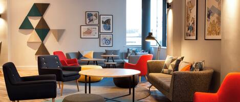 A modern lounge area with seating arrangements, artwork on the walls, and a view of the street outside.