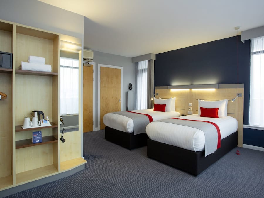 Habitación de hotel con dos camas, un armario, un escritorio y un baño.
