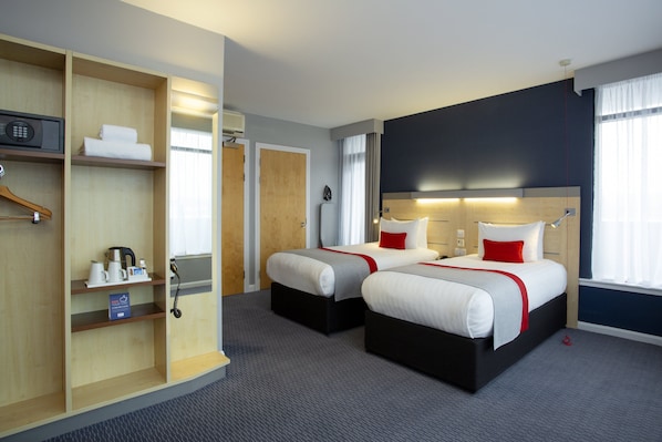 Une chambre d’hôtel avec deux lits, une armoire, un bureau et une salle de bain.
