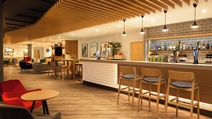 Un área de bar moderna con piso de madera, taburetes y una variedad de botellas de licor.