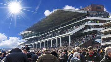 A stadium with multiple tiers of seating and a large crowd gathered outside.