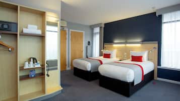 A hotel room with two beds, a minibar, a desk, and a wardrobe.