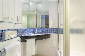 Une salle de bain avec une douche à parois de verre, un lavabo avec un porte-serviettes et un miroir.