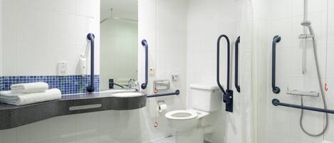 A modern bathroom with a white toilet, a sink with a mirror, and a shower area.
