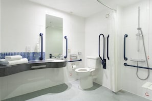 Une salle de bain moderne avec des toilettes blanches, un lavabo avec un miroir et un espace douche.