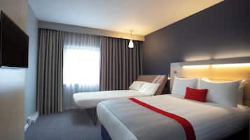 A hotel room with two beds, a large window with curtains, a flat-screen TV, and a modern headboard.