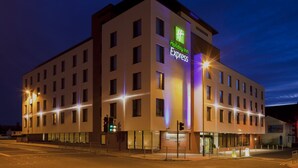 Edificio de Holiday Inn Express con un diseño arquitectónico moderno, que cuenta con múltiples ventanas y una señalización destacada.