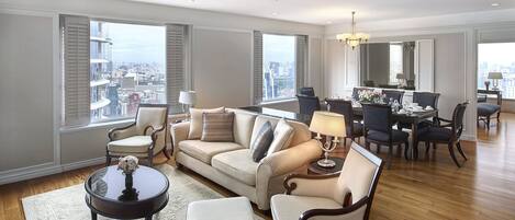 A spacious living room with a sofa, chairs, a coffee table, and a dining area with a chandelier.