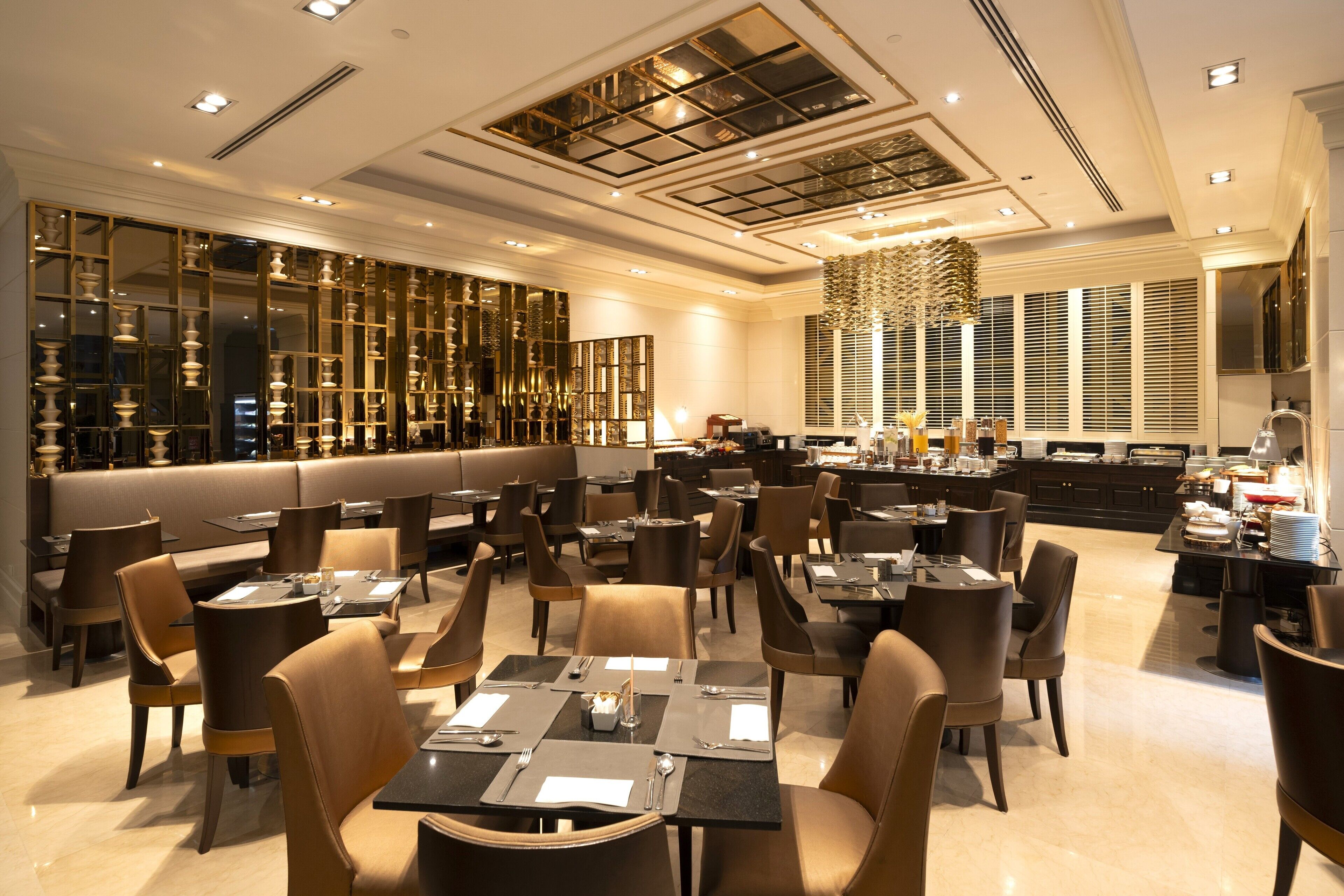 Un restaurante espacioso con techos altos, iluminación moderna y diferentes opciones de asientos, como mesas y cabinas.