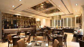 A spacious restaurant with high ceilings, modern lighting, and a variety of seating options including tables and booths.