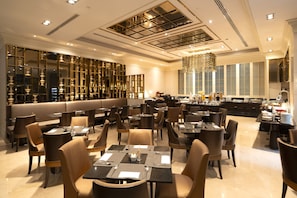 A spacious restaurant with high ceilings, modern lighting, and a variety of seating options including tables and booths.