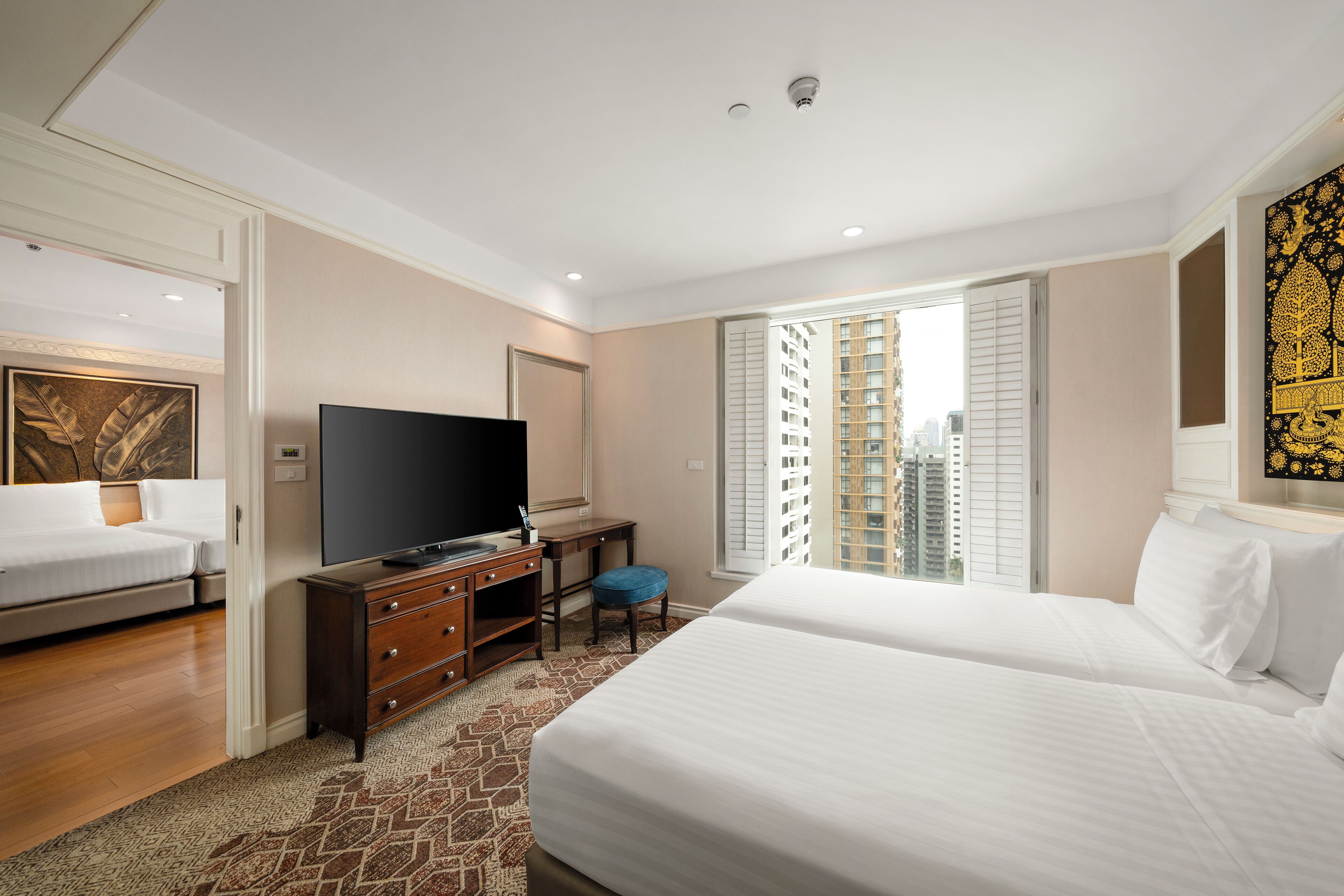 Een hotelkamer met een bed, een televisie, een bureau en een raam met uitzicht op de stad.