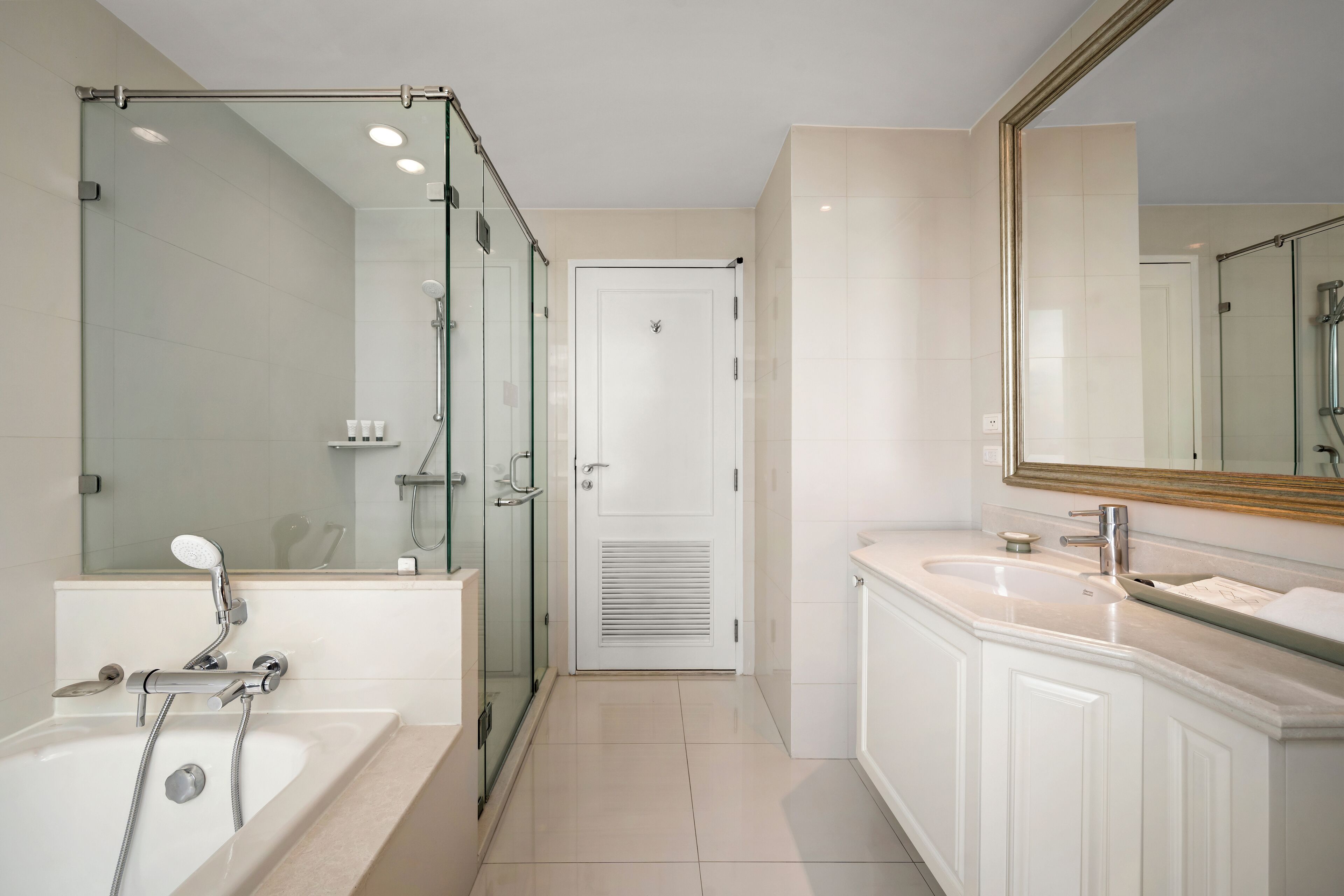 A modern bathroom with a glass-enclosed shower, a large mirror, and a white vanity with a sink.