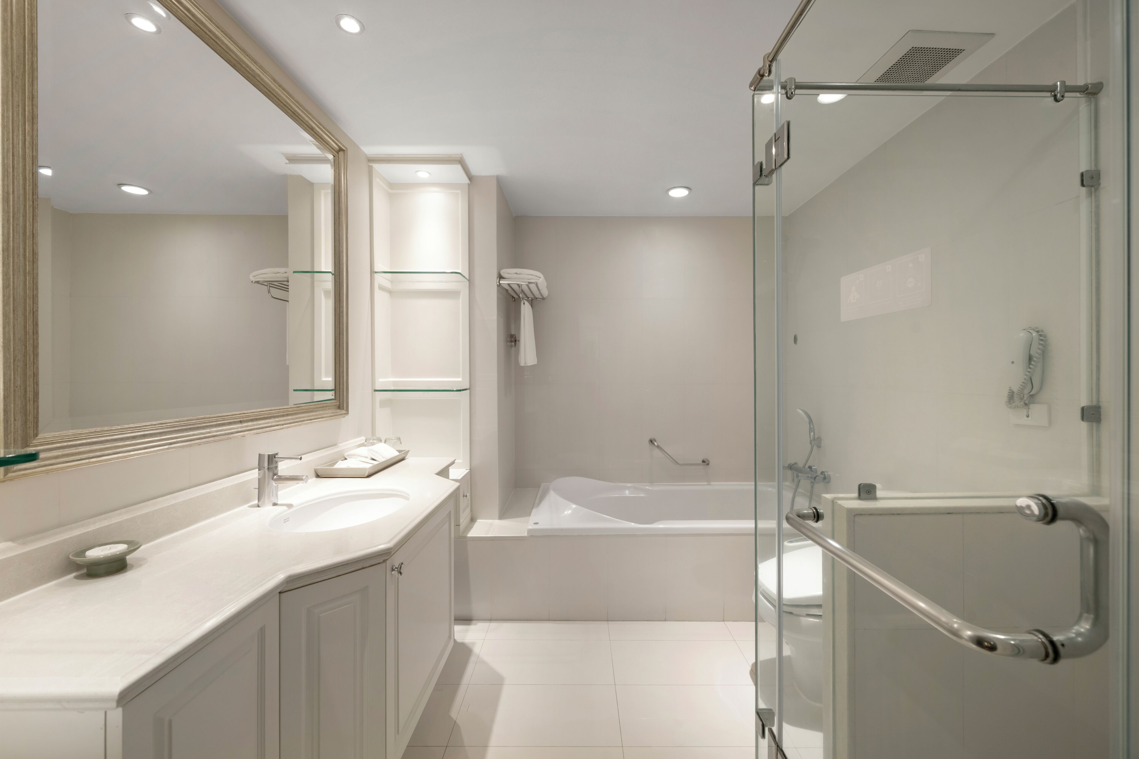 A modern bathroom with a glass-enclosed shower, a large mirror, and a white vanity with a sink and countertop.