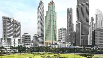 A cityscape with modern high-rise buildings, a park with manicured lawns and trees, and a body of water.