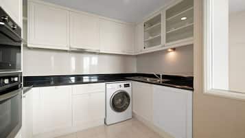 Une cuisine compacte avec des meubles blancs, un lave-linge encastré et un plan de travail noir.