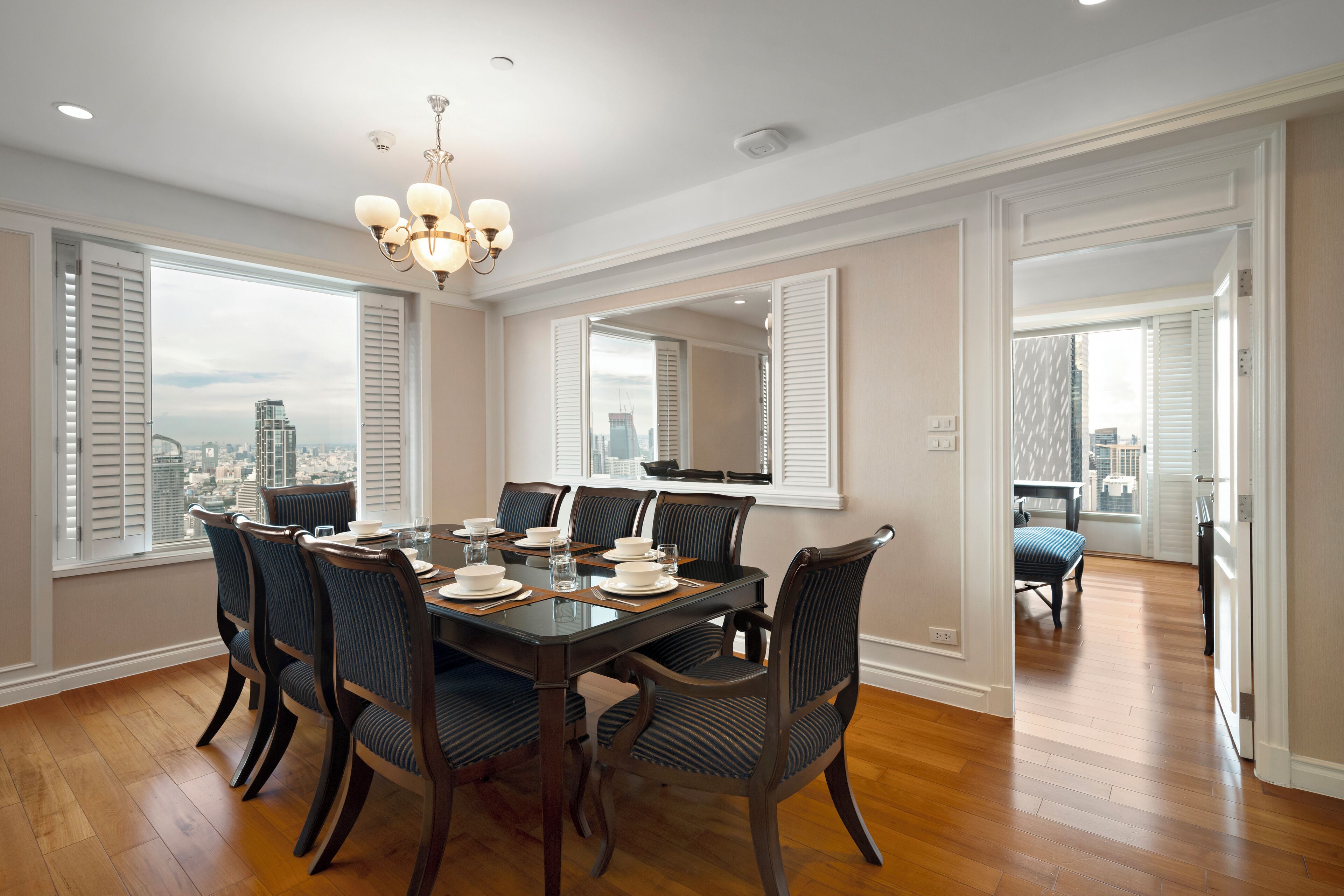 A dining room with a large table, six chairs, and a chandelier.