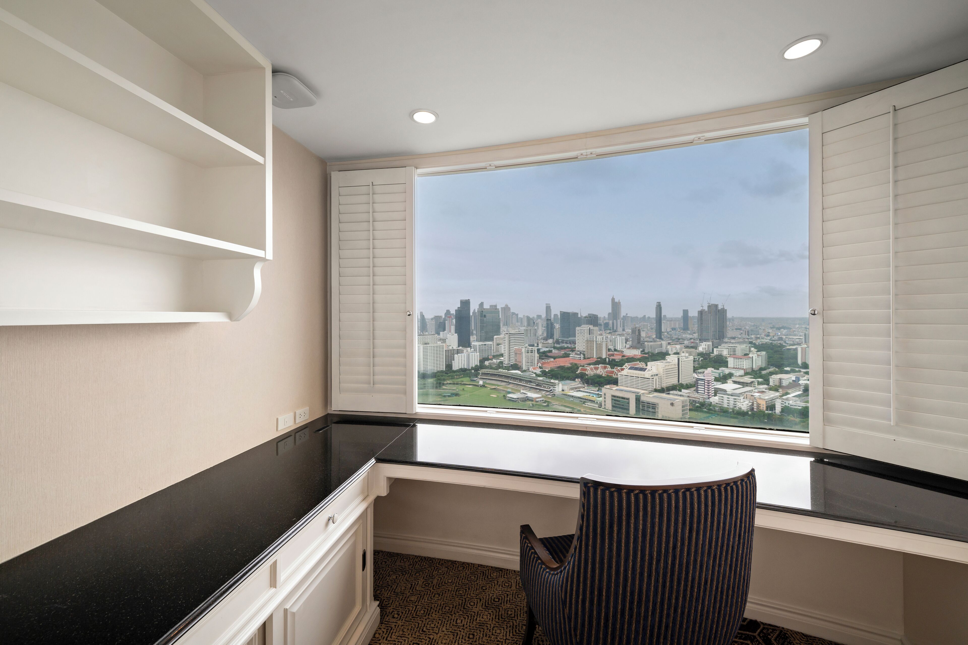 Habitación de esquina con vista a la ciudad, un escritorio y una silla.