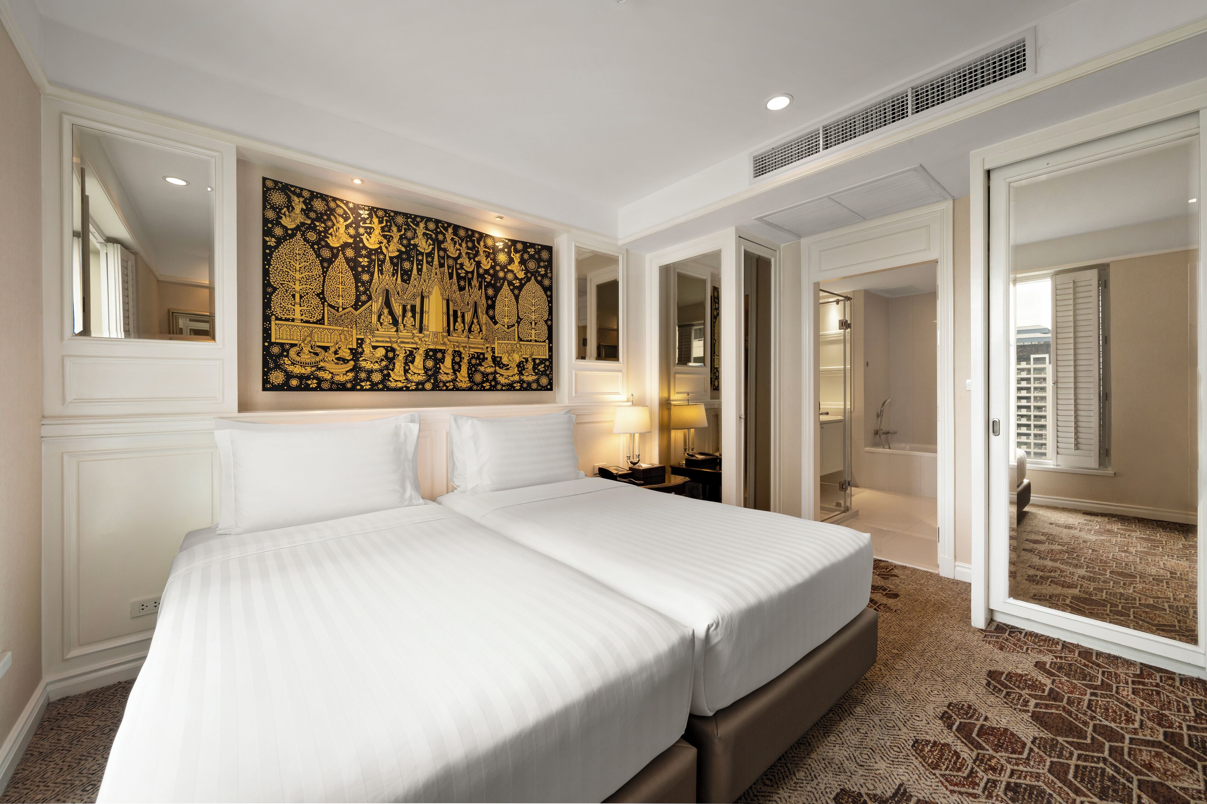 Hotelkamer met een groot bed, een decoratief kunstwerk, een nachtkastje en een zichtbare badkamer door een open deur.