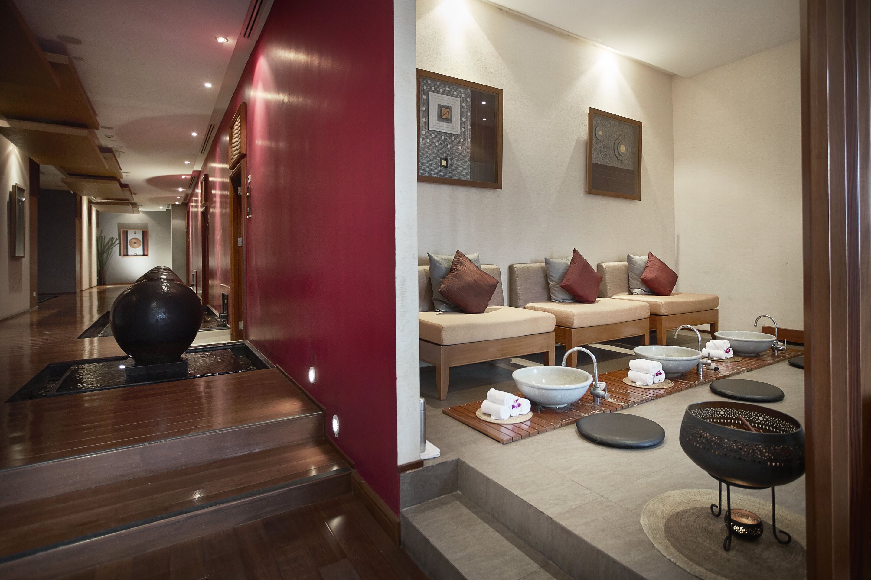 A modern spa area with a reception desk, a seating area with massage tables and chairs, and a large black bowl on the floor.