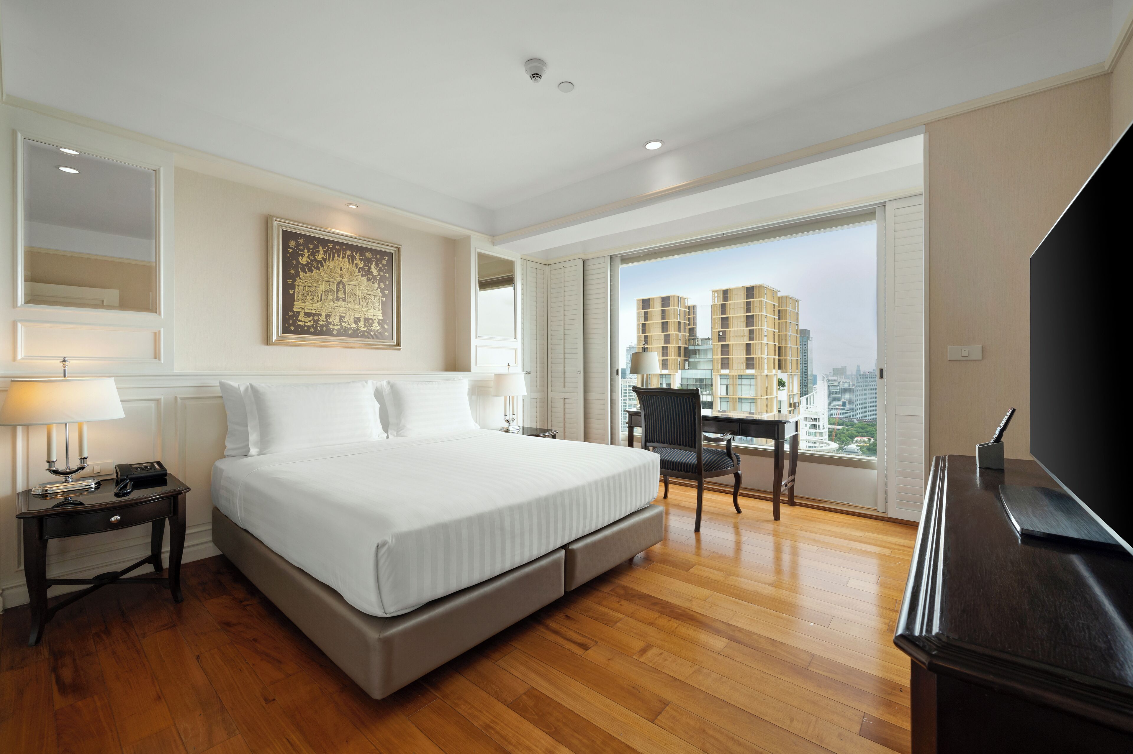 A hotel room with a large bed, a desk, and a TV.