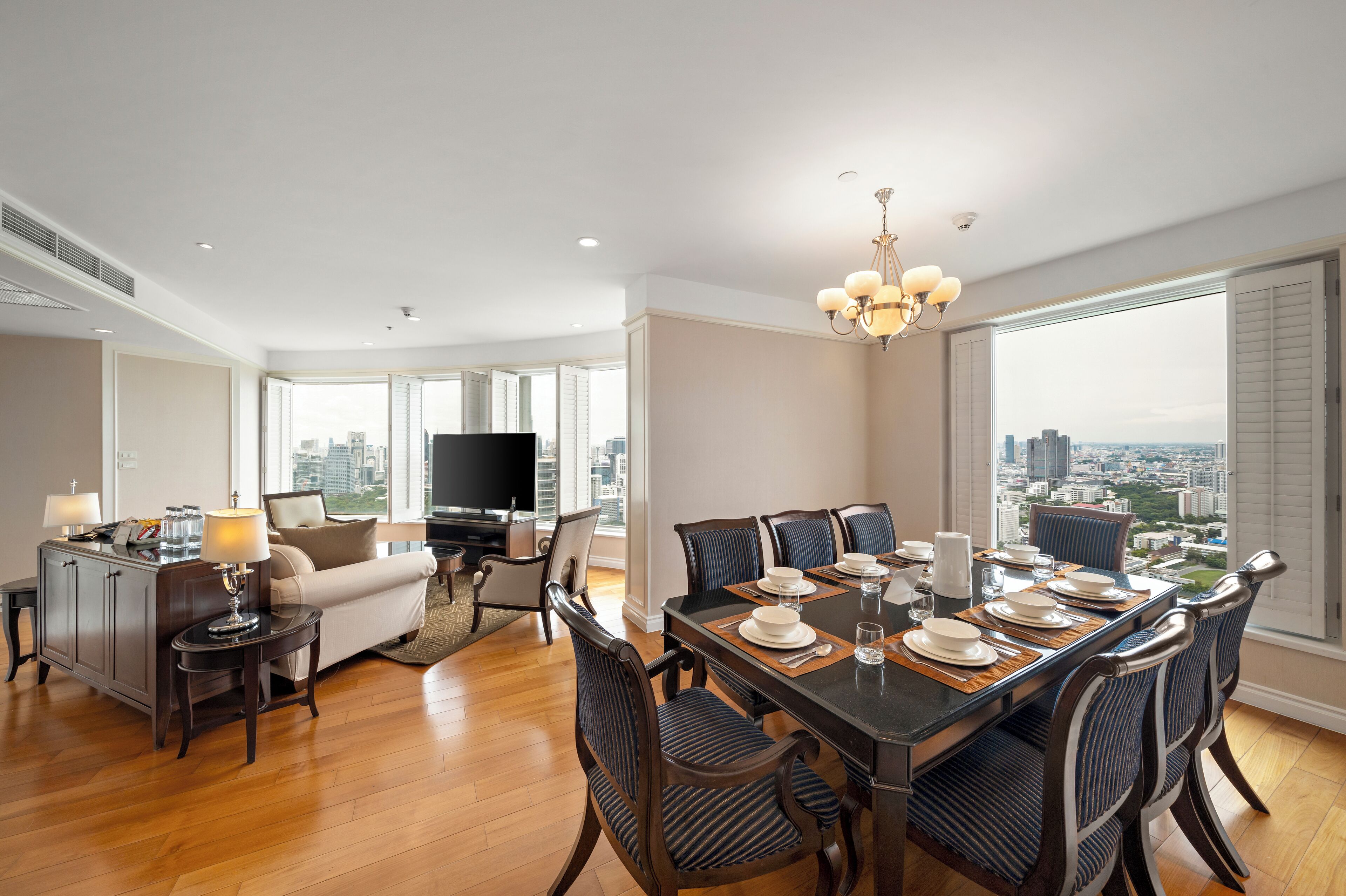 A spacious living room with a dining area, a flat-screen TV, and a city view.