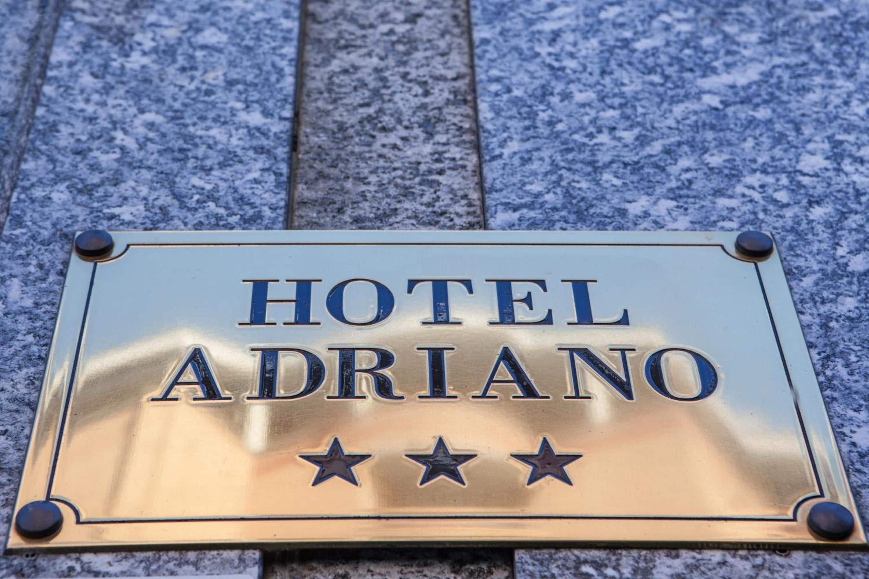 A hotel sign with the name 'HOTEL ADRIANO' and three stars.