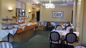 A dining area with a buffet setup, multiple tables, and chairs. - Hotel Am Kurpark Bad Salzelmen (Schönebeck)