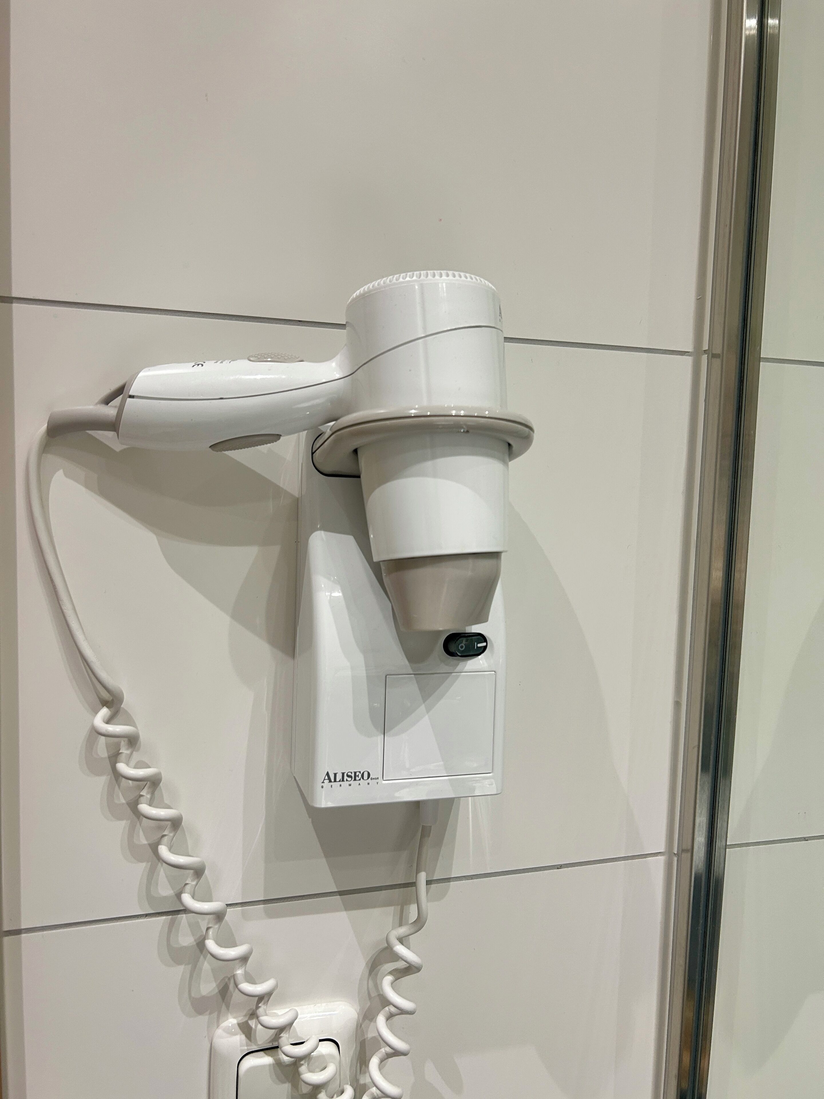 Un secador blanco fijado en una pared de azulejos.